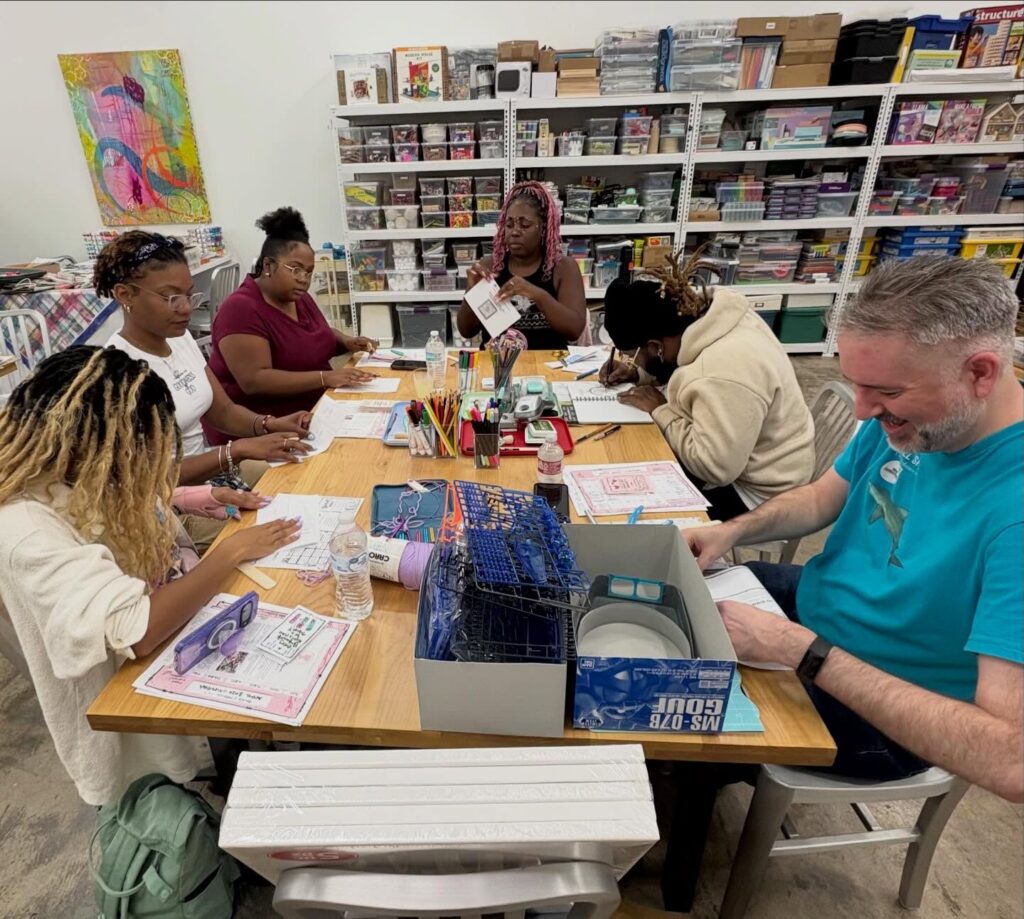 A group of people sitting around a table, working on crafts.
