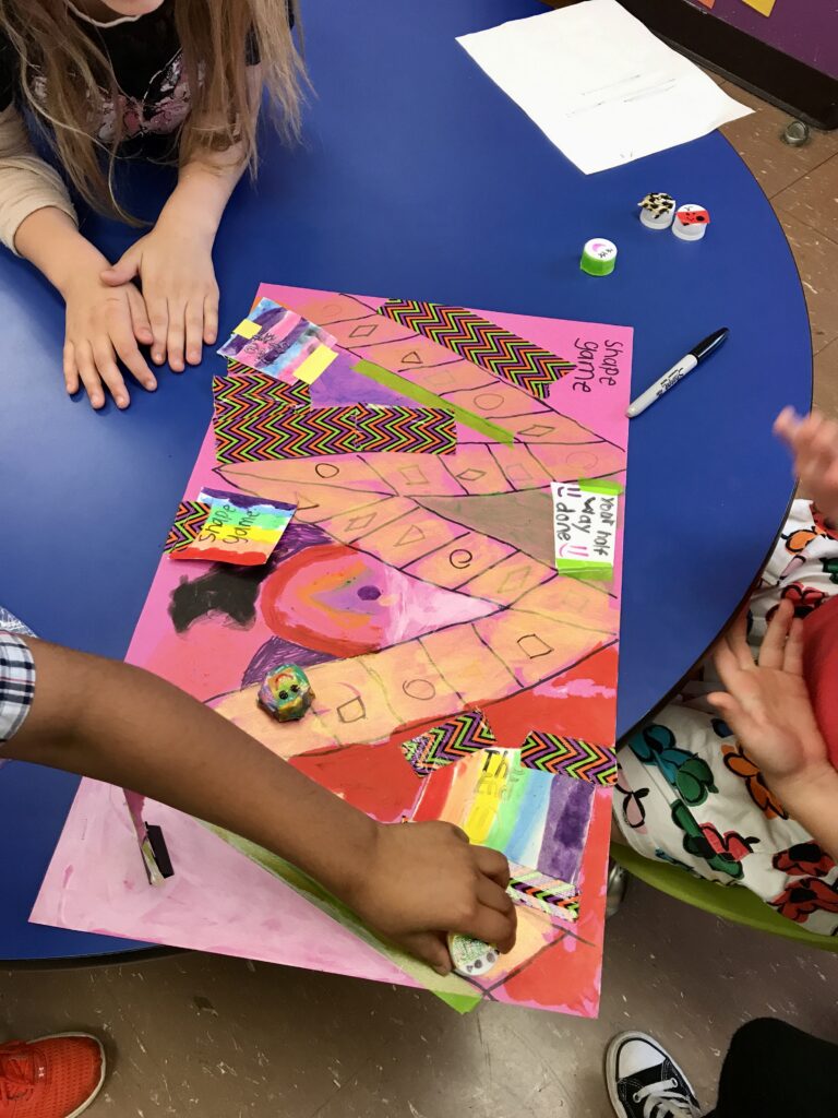 Three children working on a craft with construction paper, markers, and glue sticks.