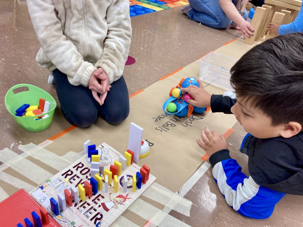 A boy is playing with a toy robot while another child observes.